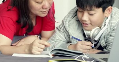 Çocuk evde ödevini yaparken Asya Anne küçük oğlu yardımcı olur.