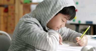 Asyalı çocuk ile ödevlerini yapıyor yüzünü gülümseme ve ev hevesli olmak mutlu, Dolly taşıma soldan sağa .