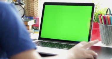 Genç çocuğun dizüstü bilgisayarda izlerken omuz görünümü üzerinde Dolly içinde. Yeşil ekran teknolojisi kullanılıyor. Chroma anahtar laptop.