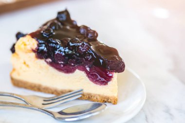 Beyaz mermer masada beyaz plaka üzerinde yaban mersini soslu peynirli kek parçası.