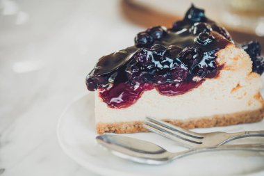 Beyaz mermer masada beyaz plaka üzerinde yaban mersini soslu peynirli kek parçasının kapatın. Kopya alanı ile Vintage tarzı .