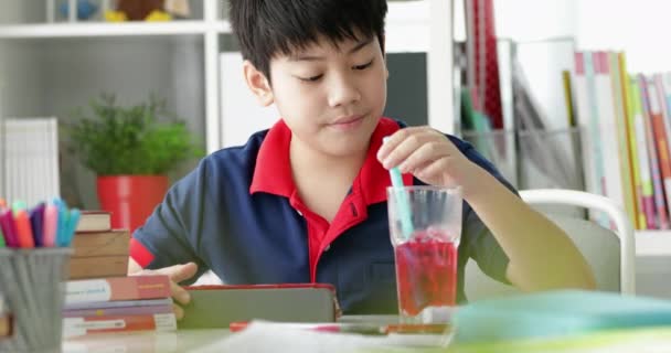 Азиатский Мальчик Пьет Смотрит Планшетном Компьютере Дома — стоковое видео