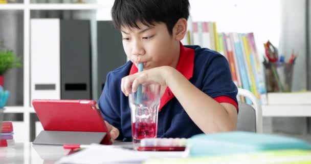 Asiatischer Junge Trinkt Und Schaut Hause Auf Tablet Computer — Stockvideo