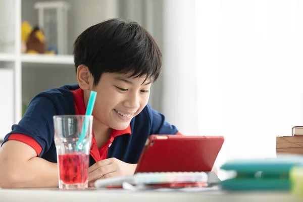 アジアのかわいい少年の笑顔を自宅でタブレット コンピューターで見て — ストック写真