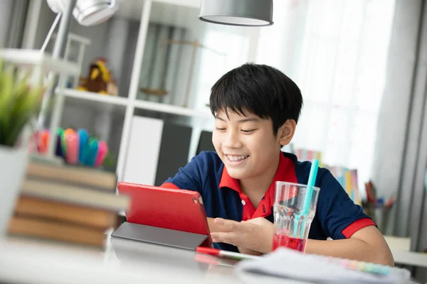 Asian cute boy watching on tablet computer with smile face  at home.