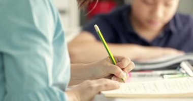 Sevimli Asya teen çocuk ödevlerini yapıyor ve bir kamera gülümseme ile seyir evde yüz.