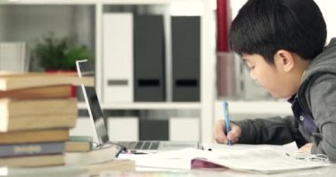 Sevimli Asya teen çocuk ile dizüstü bilgisayar vasıl ev ödevlerini yapıyor.