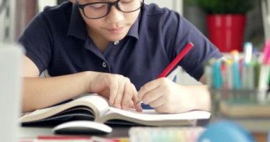 Gözlük camı waring ve ödevini evde yapıyor Asyalı çocuk.