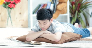 Mutlu Asyalı çocuk gülümsemek yüz kitap okuma. oturma odasında. 