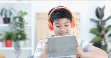 Tablet bilgisayarınızla gülümsemek yüz evde oynarken Asya öncesi gençler.