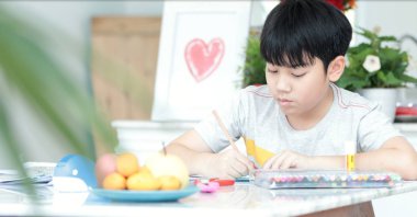 Kalem tutan ve ödevini evde yazma mutlu Asya sevimli çocuk el.