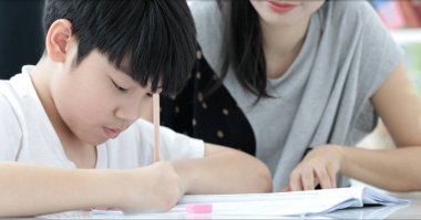 Oturma odasında ödev oğlu ile ciddi Asya anne. Anne oğlu öğretir nasıl yapılır dahi.