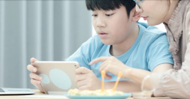 Asya ailesi genç anne oğluyla bir cep telefonu veya smartphone ile oynamak .