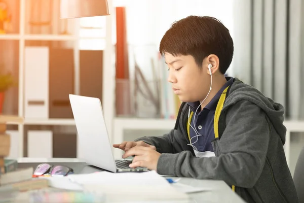 亚洲逗人喜爱的男孩使用笔记本电脑与阳光在早晨在家 — 图库照片