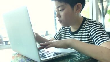 Dizüstü bilgisayarda yazarak ağır çekim 4 k mutlu Asyalı çocuk. 