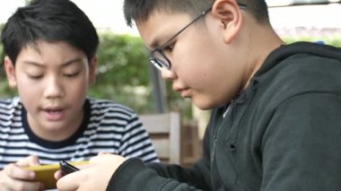 Yavaş hareket 4 k mutlu Asyalı çocuk birlikte akıllı telefonda mobil oyunu online oynamak. Çocuk ve arkadaş eğlenmek stratejisi ile görüşmek.