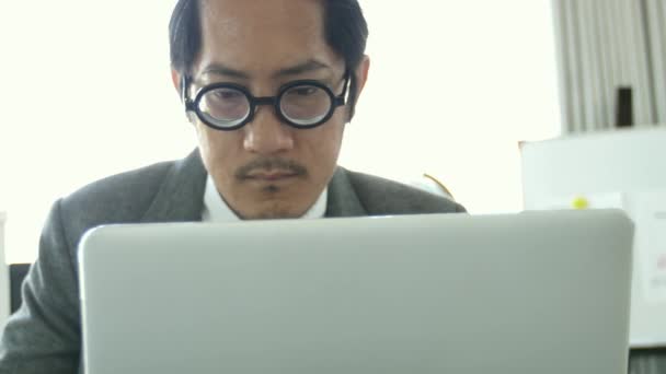 ビジネスマンのオフィスで眼鏡を着てスローモーション アジア ビジネス男をラップトップ コンピューターでオフィス で動作して — ストック動画