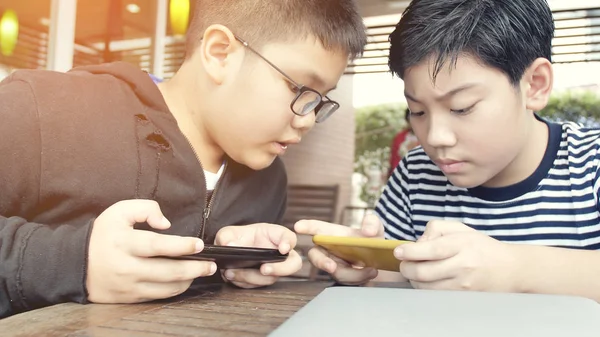 愉快的亚洲男孩玩手机游戏在线智能手机在一起 男孩和朋友与战略有乐趣 — 图库照片