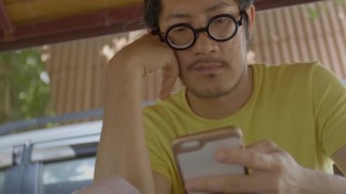 Yavaş hareket 4 k smartphone kullanarak rahat Asya adam. Posta, sohbet veya haber online kontrol ediyor.