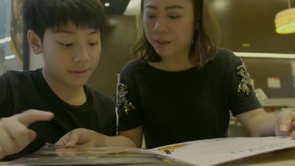 Câmera Lenta Menino Bonito Asiático Com Livro Menu Leitura Mãe — Vídeo de Stock