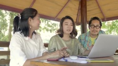 Güzel Asyalı kadın gösterir ilginç şeyler onlar iyi zaman bahçede iken onun arkadaşlarına Her smartphone. Gülüyorlar, şaka .