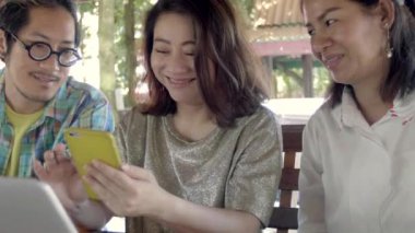 Güzel Asyalı kadın gösterir ilginç şeyler onlar iyi zaman bahçede iken onun arkadaşlarına Her smartphone. Gülüyorlar, şaka .