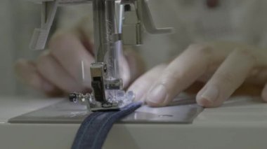 Bir kadın bir önlük ile bir dikiş makinesi dikiş görüntülerini kapat