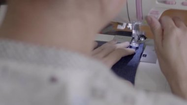 Bir kadın bir önlük ile bir dikiş makinesi dikiş görüntülerini kapat