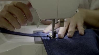 Bir kadın bir önlük ile bir dikiş makinesi dikiş görüntülerini kapat