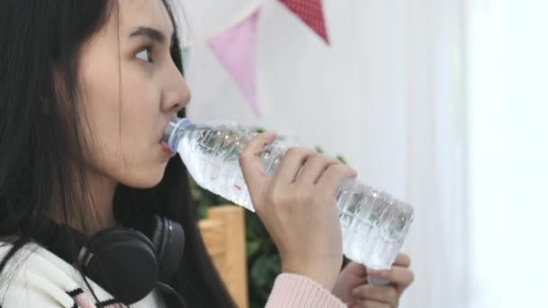 アジアの女性の美しいボトルから水を飲むのスローモーションが家で喜んでください — ストック動画