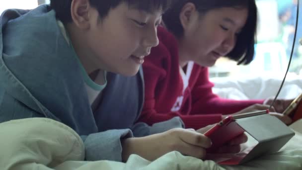 慢动作的快乐亚洲男孩和女孩玩游戏在平板电脑与微笑的脸 — 图库视频影像