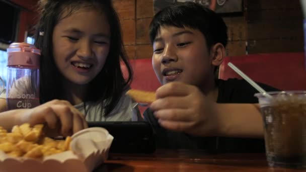 Felice Bambino Asiatico Guardando Sul Cellulare Godere Mangiare Fuochi Patate — Video Stock