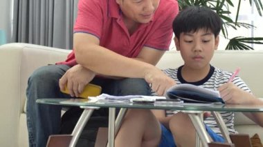 Asya baba ve oğul masada oturma odasında ödev .