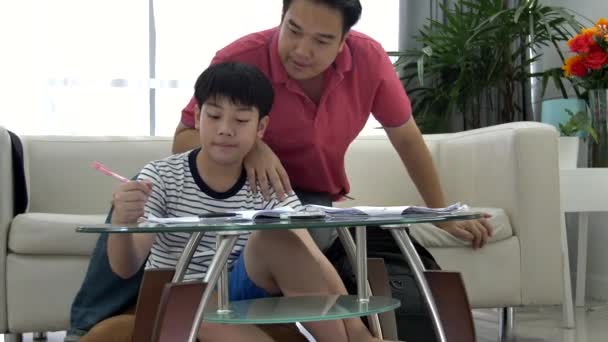 亚裔父亲和儿子在客厅的桌子上做作业 — 图库视频影像