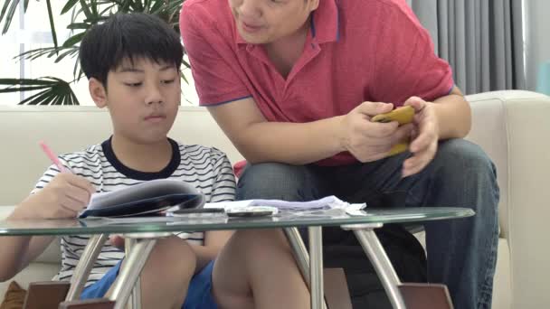 アジアの父と息子の宿題をリビング ルームのテーブルの上 — ストック動画