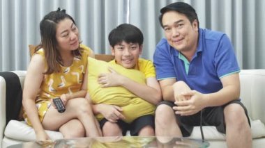 Asya Aile Baba Anne ve oğlu kanepede, ağır çekim, Looking kamera gülümseme ile yüz.