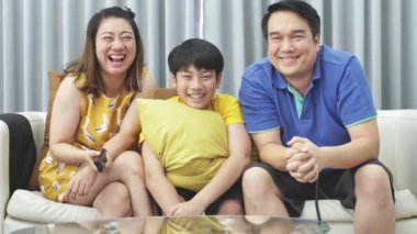 Asya Aile Baba Anne ve oğlu kanepede, ağır çekim, Looking kamera gülümseme ile yüz.