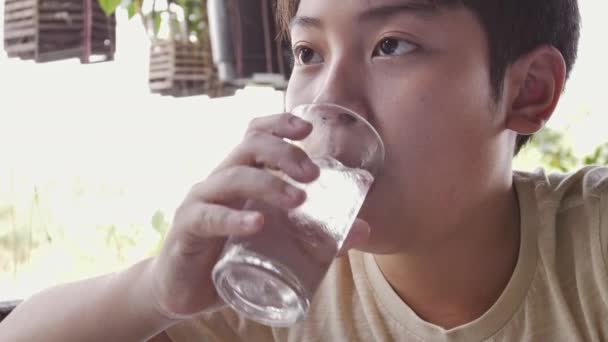 アジアの少年のスローモーションは 朝食後 ガラスから水を飲む 近くには水のガラスの十代の少年 — ストック動画