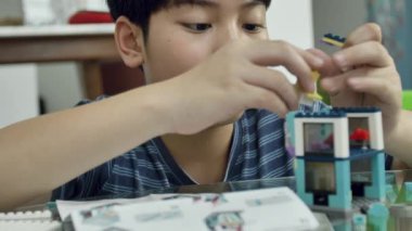 Asyalı çocuk gülümsemek yüz plastik blok evde oynarken yavaş. 4k
