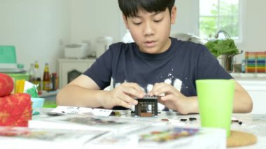 Asyalı çocuk gülümsemek yüz plastik blok evde oynarken yavaş. 4k