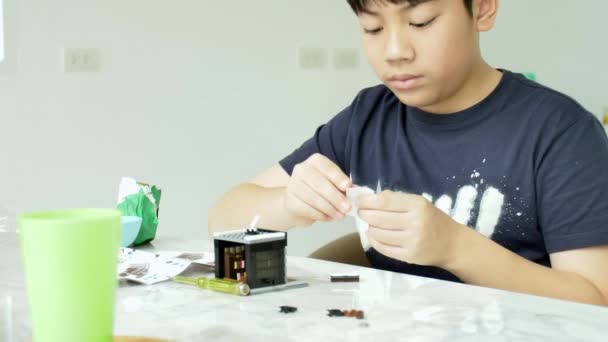 亚洲男孩在家里玩塑料块的慢动作带着微笑的脸 — 图库视频影像