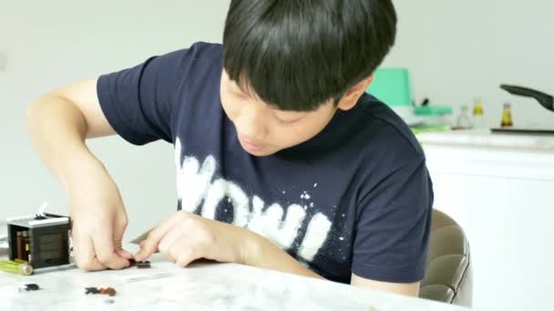 亚洲男孩在家里玩塑料块的慢动作带着微笑的脸 — 图库视频影像