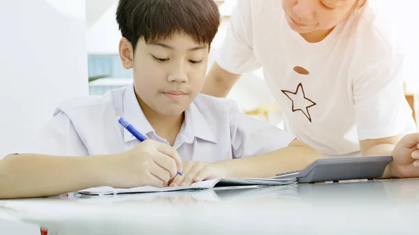 Asijská Matka Pomáhá Její Syn Dělat Domácí Úkoly Bílém Stole — Stock fotografie