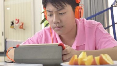 Mutlu asyalı çocuk tablet bilgisayarda oynarken, çocuk elma parçası yeme ve tablette izlerken.
