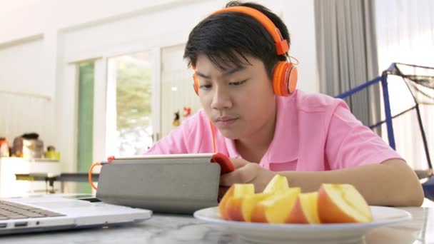 Glücklicher Asiatischer Junge Spielt Auf Tablet Computer Junge Isst Stück — Stockvideo