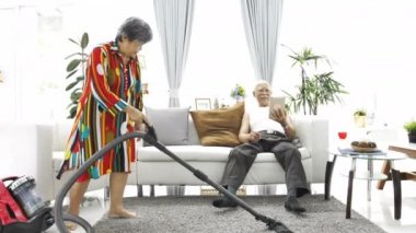 Tablet bilgisayar ve üst düzey kadın evde zemin vakumlama oynarken mutlu Asya komuta sizde. 4 k yavaş hareket .