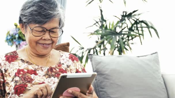 アジア高齢女性の自宅 タブレット コンピューター技術で幸せな祖母を手に使用して スローモーション ドリー ショット — ストック動画