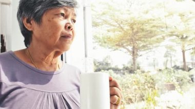 4 k mutsuz yalnız Asyalı kadın kıdemli bir fincan kahve ev, ağır çekim yalnız ile 