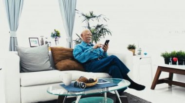 Asya kıdemli evde, tablet bilgisayar teknolojisi ile mutlu büyükbaba el kullanarak beyaz bıyıklı adam. Ağır çekim 4k, Dolly vurdu.