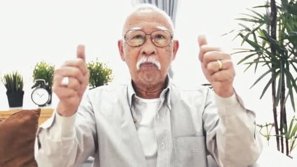 Thumps を放棄古いアジア人からのフロント ビュー アジア シニア ジェスチャーを親指を作り 笑顔で自宅に対する笑顔の のスローモーション — ストック動画